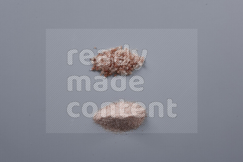 Bunches of table salt, coarse sea salt, fine himalayan salt and coarse himalayan salt on grey background