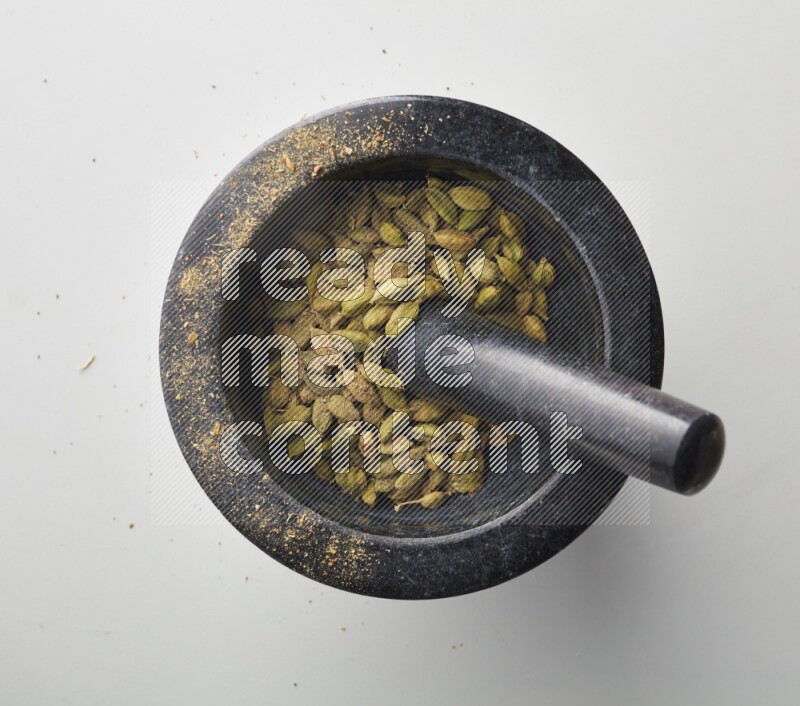 Top-view shot of Cardamon in herbs crusher on white background