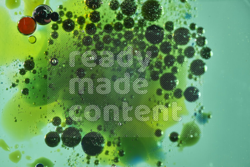 لقطات مقربة لقطرات ألوان مائية حمراء وخضراء وصفراء على سطح الزيت على خلفية خضراء