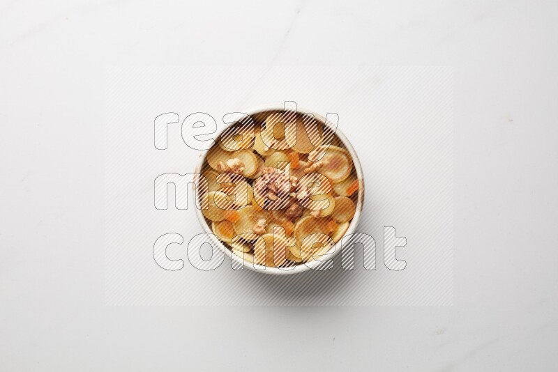 Top-view shot of walnut and apricot cereal pancakes in a round bowl on white background