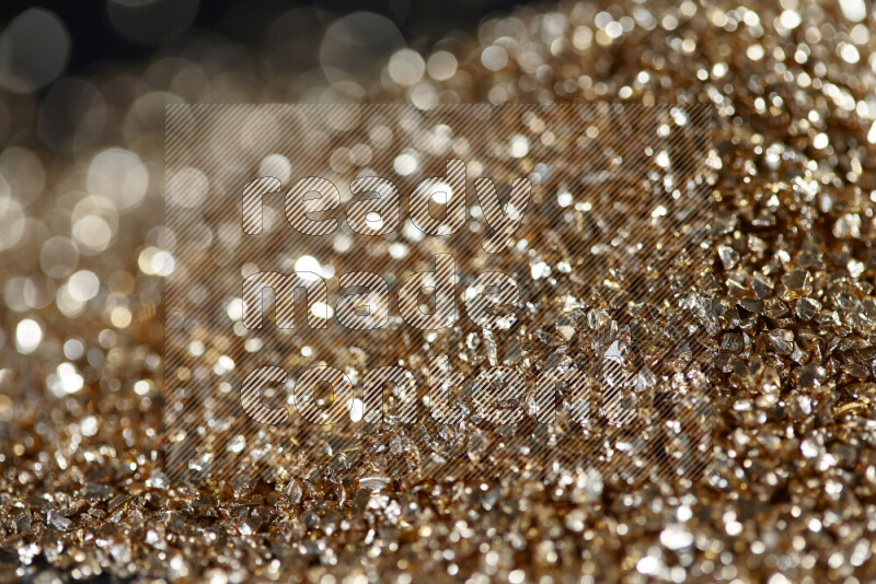 Gold shimmering fragments of glass scattered on a black background