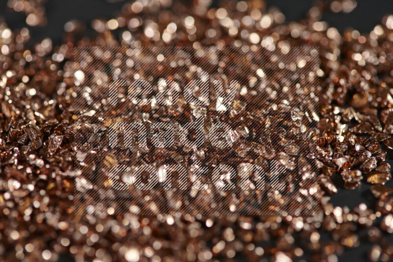 Bronze shimmering fragments of glass scattered on a black background
