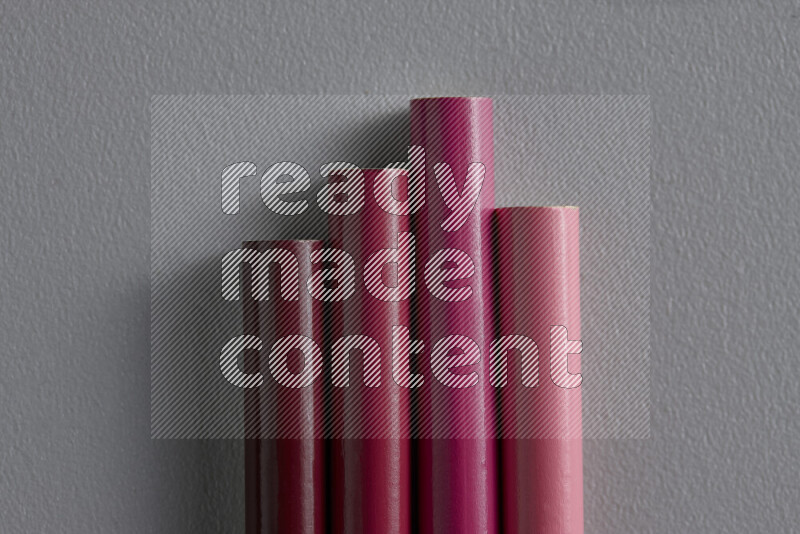 A collection of sharpened colored pencils arranged showcasing a gradient of pink hues on grey background