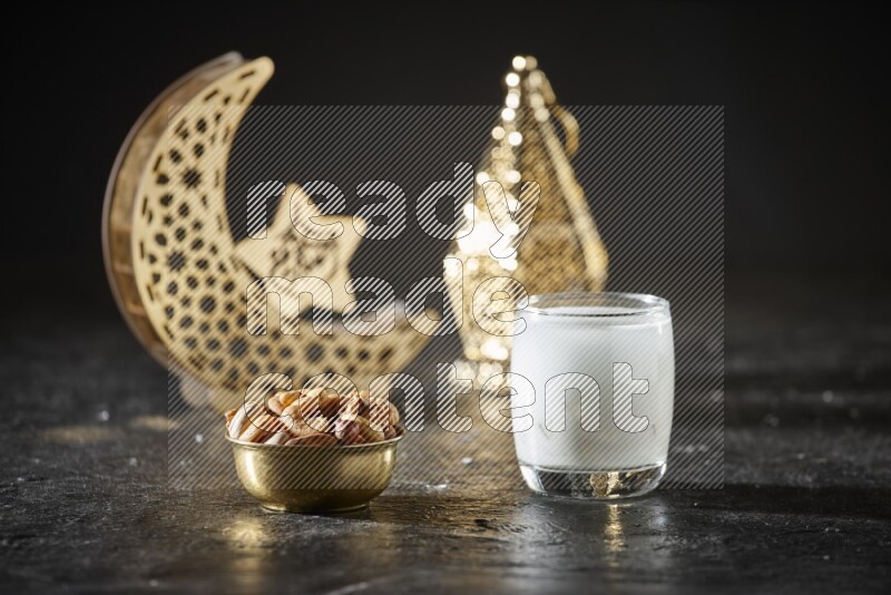 Nuts in a metal bowl with sobia beside golden lanterns in a dark setup