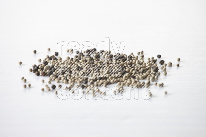 حبوب الفلفل المختلطة السوداء والبيضاء على أرضية بيضاء