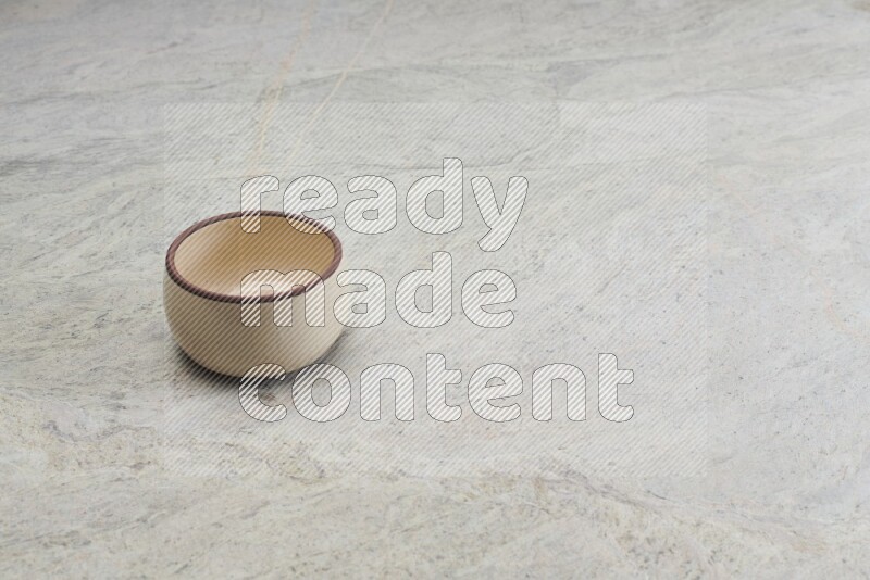 A beige pottery oven bowl on grey marble background