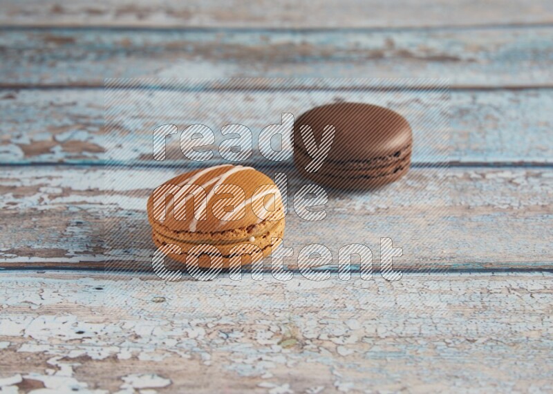 45º Shot of of two assorted Brown Irish Cream, and Brown Dark Chocolate macarons on light blue background