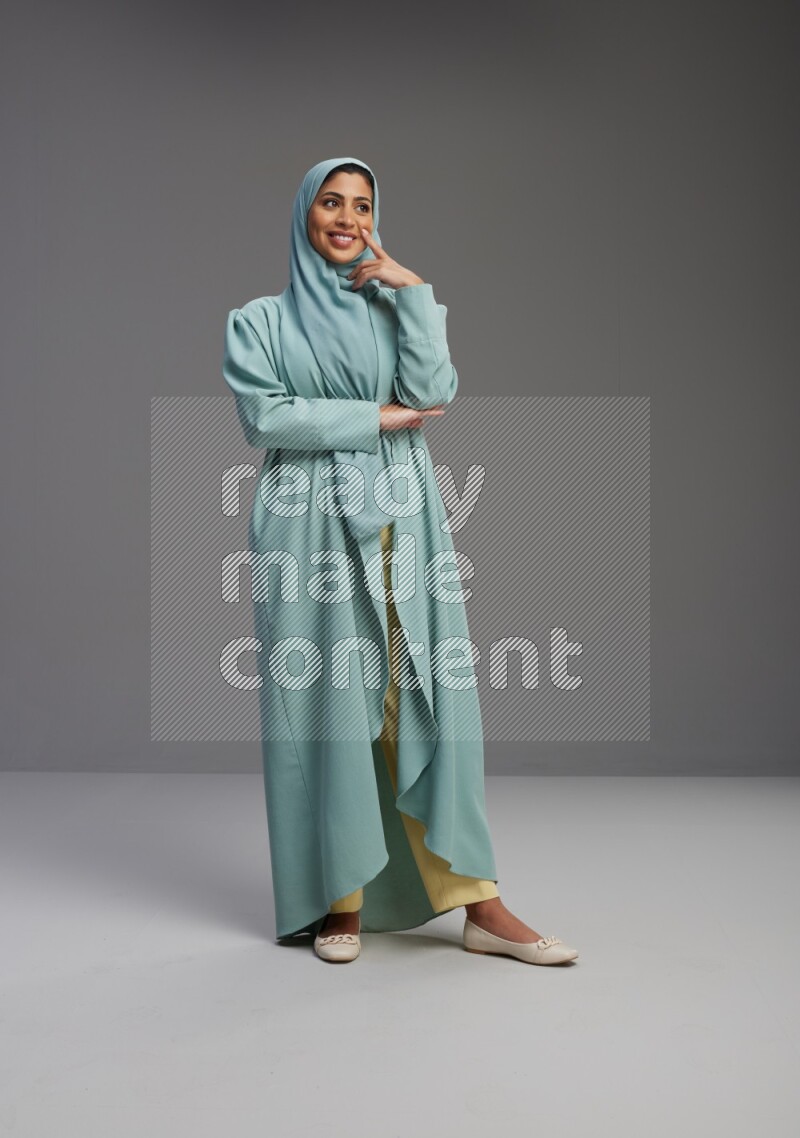 Saudi Woman wearing Abaya standing interacting with the camera on Gray background