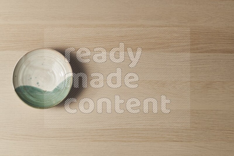 A multicolored pottery plate on light wooden background
