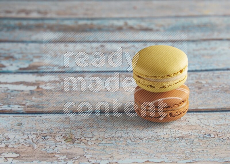 45º Shot of of two assorted Brown Irish Cream, and Yellow Lime macarons on light blue background