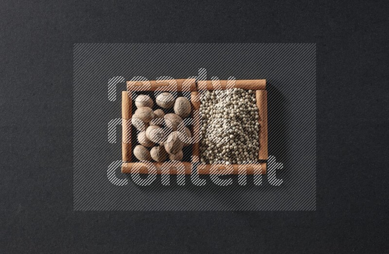 2 squares of cinnamon sticks full of nutmeg and white peppers on black flooring