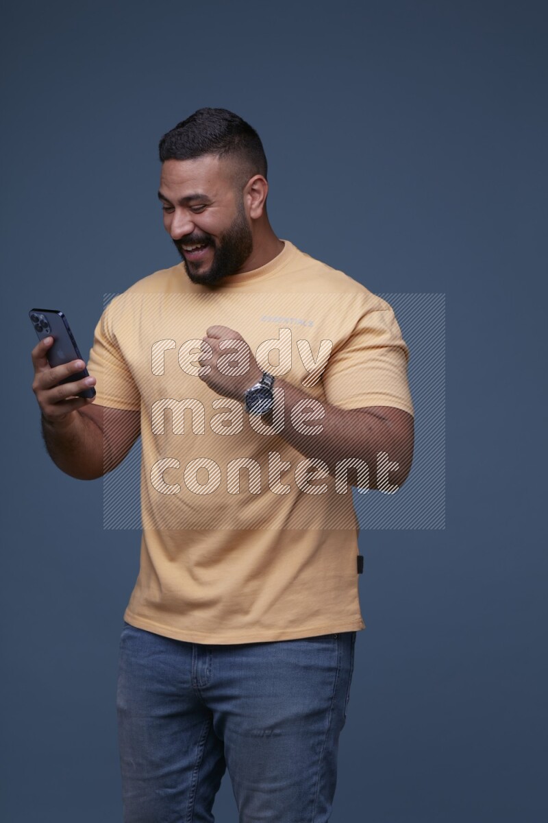 A man Texting on his phone in Blue Background wearing Orange T-shirt