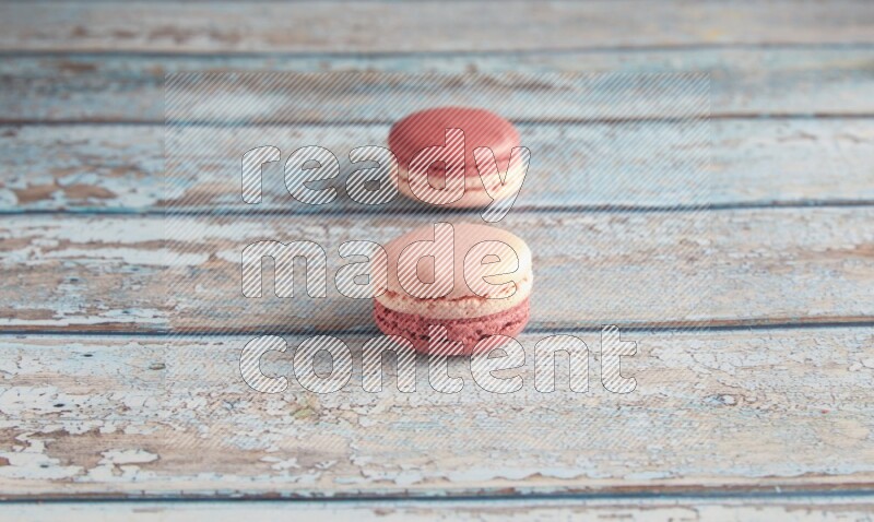 45º Shot of two Pink Litchi Raspberry macarons on light blue wooden background