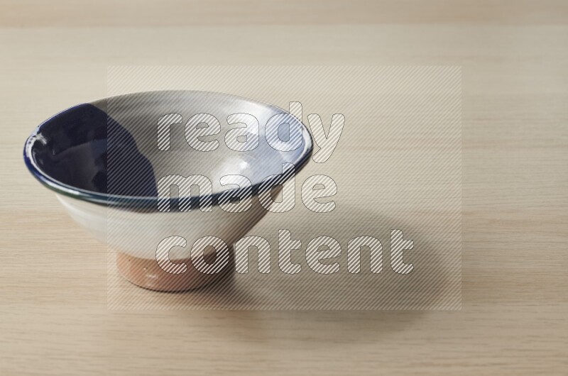 A multicolored pottery bowl on light wooden background