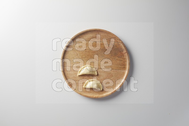 Two Sambosas on a wooden round plate on a white background