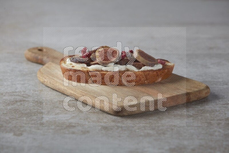 figs slices  with cream cheese on toasted sourdough slice on a wooden board on textured grey background