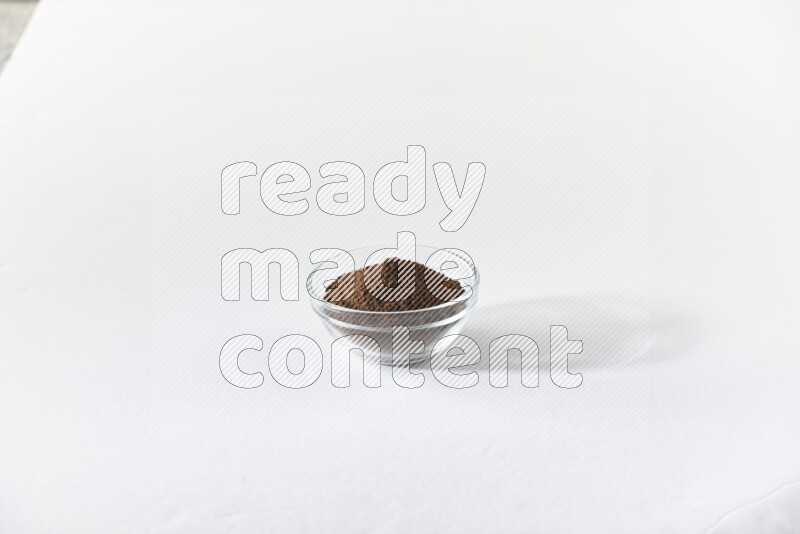 وعاء زجاجي ممتلئ ببودرة القرنفل على أرضية بيضاء