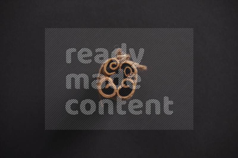 4 أعواد من القرفة مربوطة علي خلفية سوداء