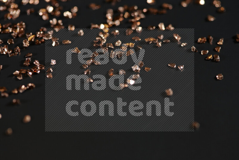 Bronze shimmering fragments of glass scattered on a black background