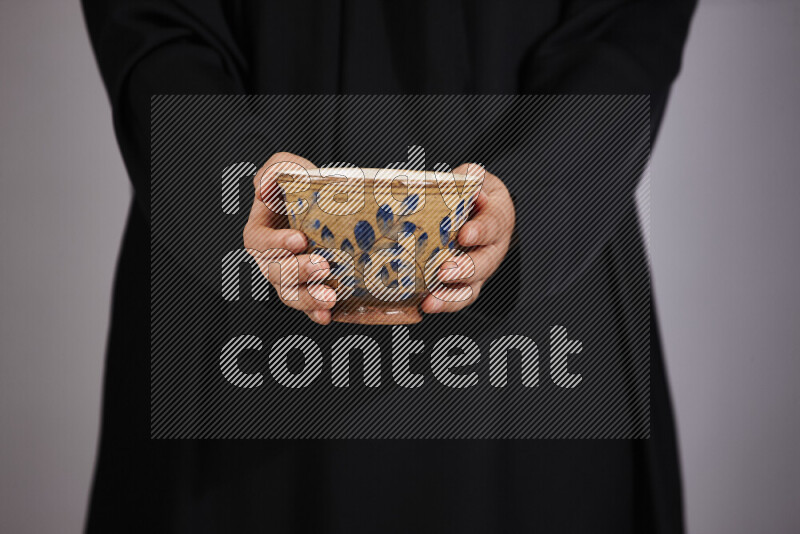 A woman in black abaya holding different pottery essentials in different positions