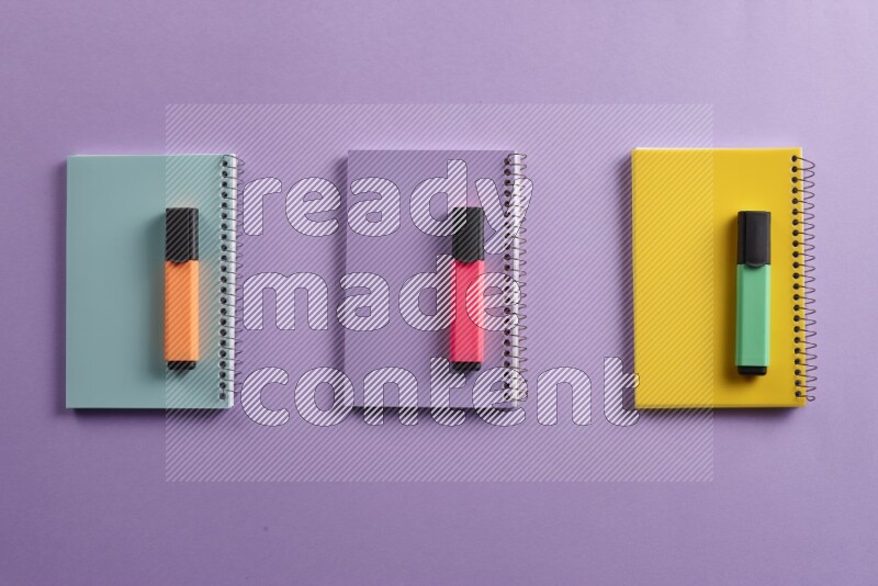 Multicolored notebooks with different school supplies on purple background