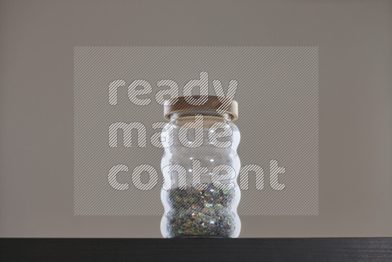 Sequins in a glass jar on black background