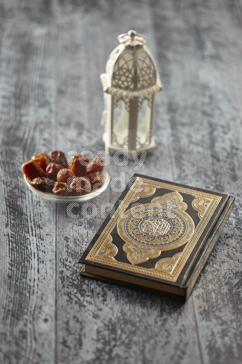 A white lantern with different drinks, dates, nuts, prayer beads and quran on grey wooden background