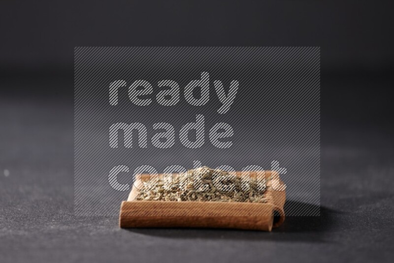 A single square of cinnamon sticks full of cumin on black flooring