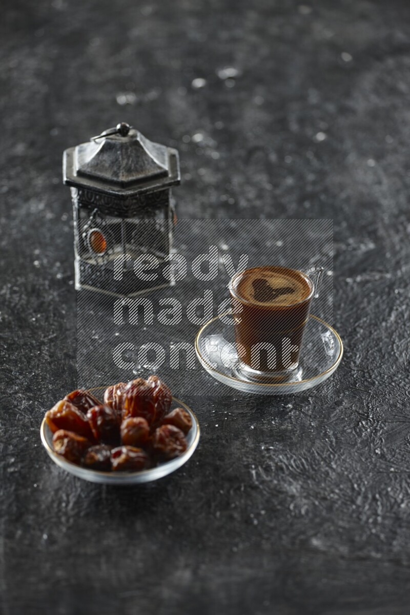 A silver lantern with different drinks, dates, nuts, prayer beads and quran on textured black background