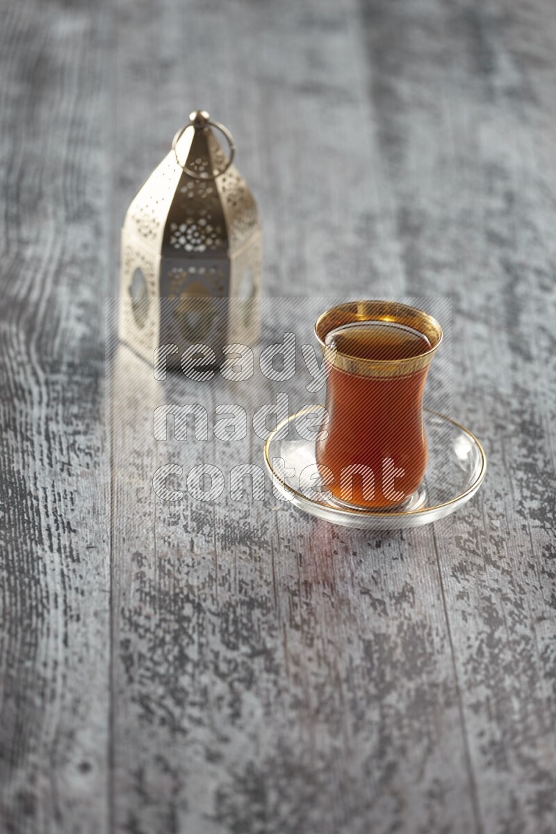 A silver lantern with different drinks, dates, nuts, prayer beads and quran on grey wooden background