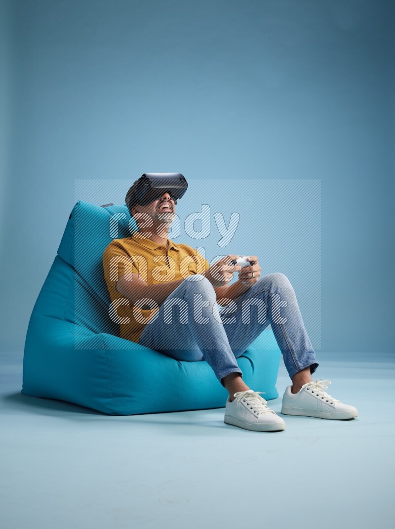 A man sitting on a blue beanbag and gaming with VR
