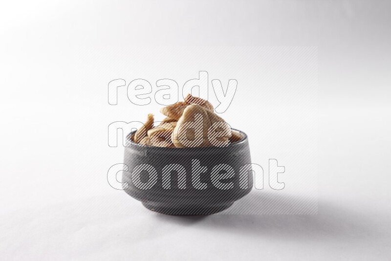 Dried figs in a black pottery bowl on white background