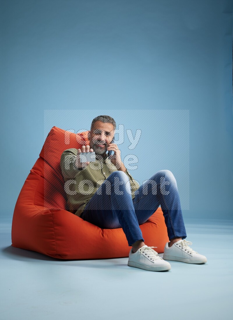 A man sitting on an orange beanbag and holding ATM card
