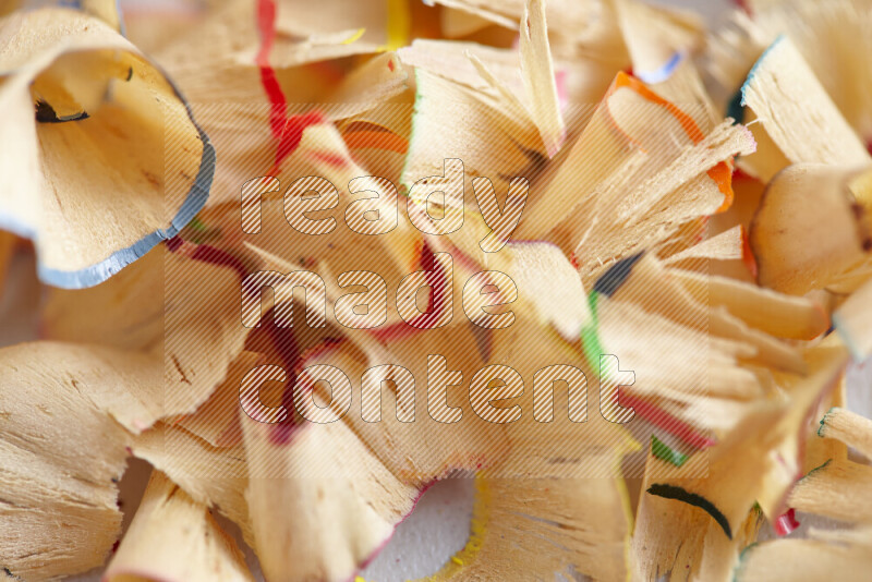 A close-up showing a small pile of pencil shavings with varied color edges on grey background