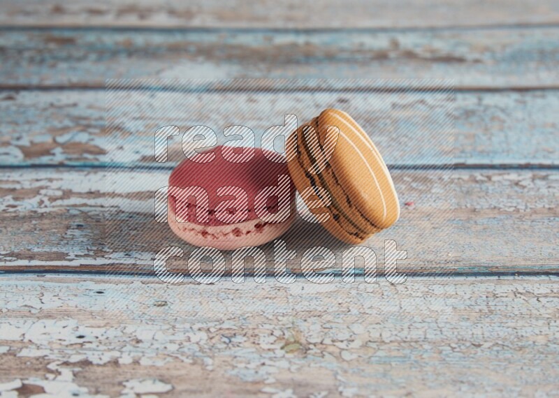 45º Shot of of two assorted Brown Irish Cream, and Pink Litchi Raspberry macarons on light blue background