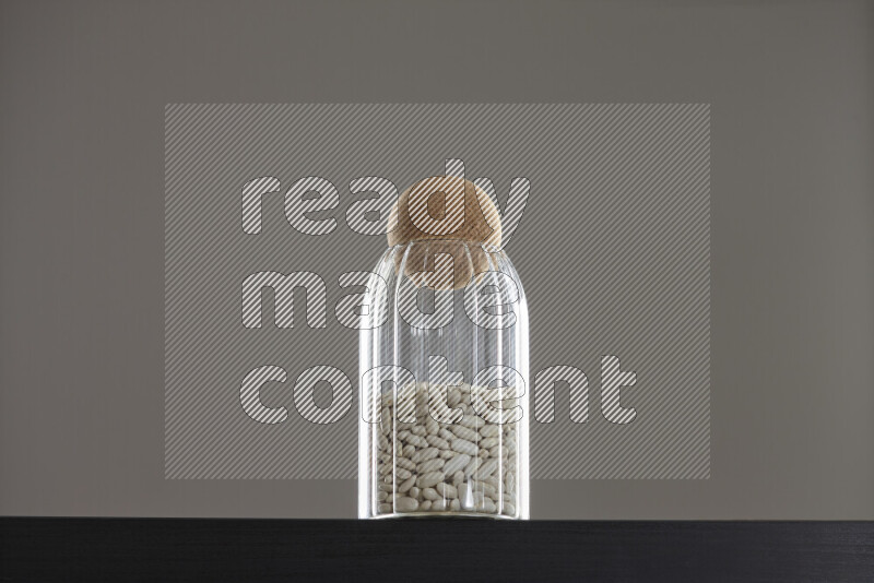 White beans in a glass jar on black background