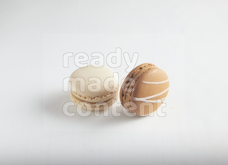 45º Shot of of two assorted Brown Irish Cream, and White Caramel fleur de sel macarons on white background