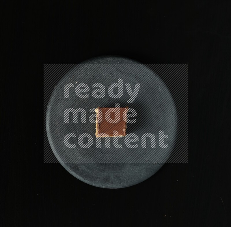 تشكيلة من الحلويات في طبق فخاري أسود على خلفية سوداء