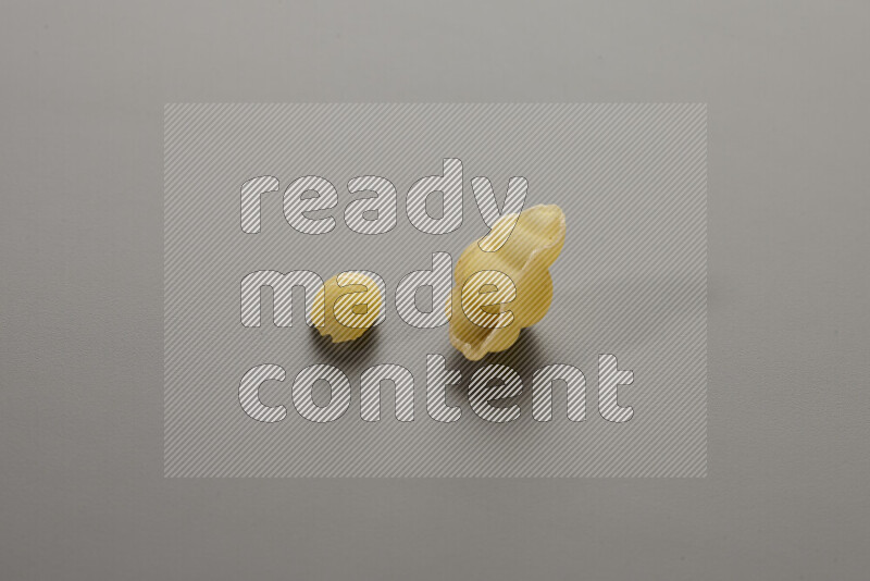 Shells pasta with other types of pasta on grey background