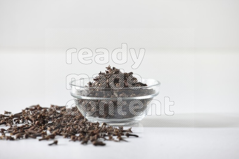 A glass bowl full of cloves on a white flooring
