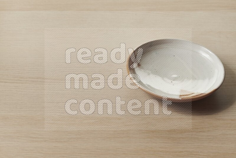 A multicolored pottery plate on light wooden background