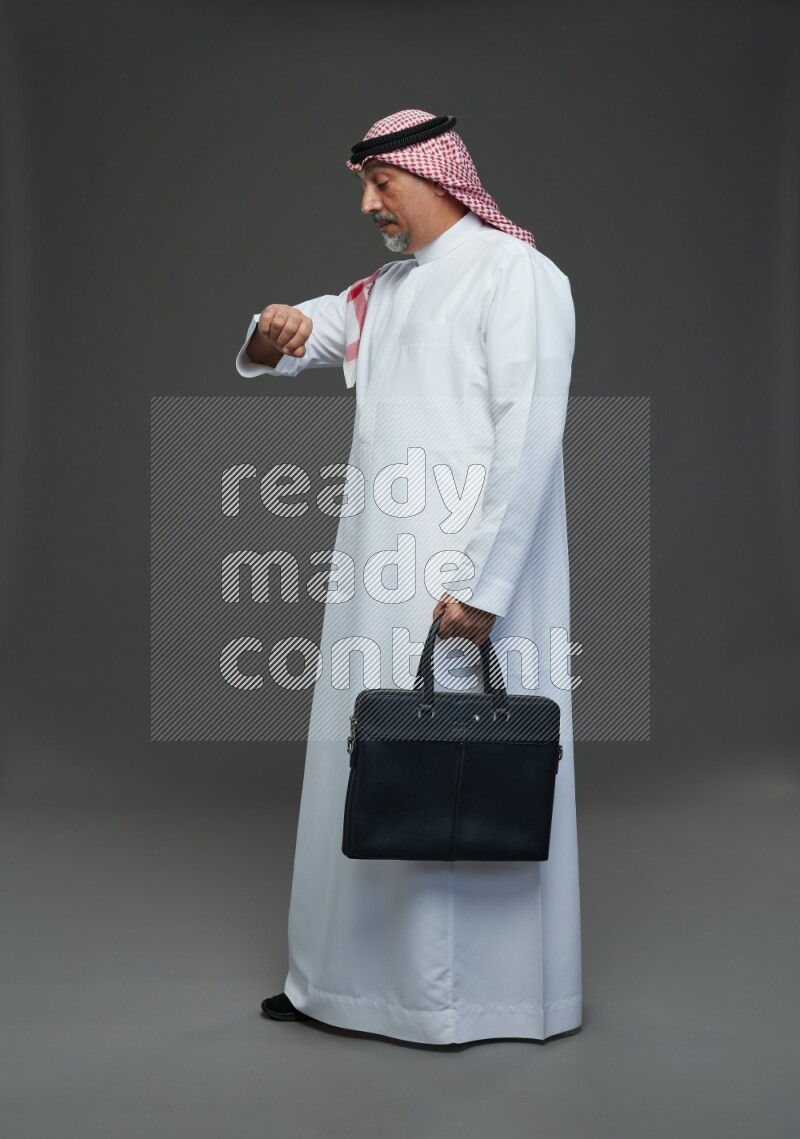 Saudi man with shomag Standing holding bag on gray background