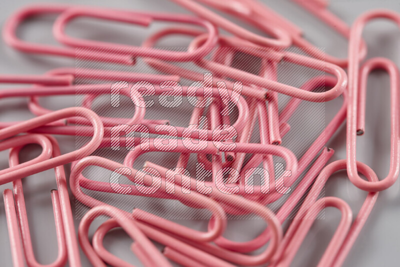 Pink paper clips isolated on a grey background