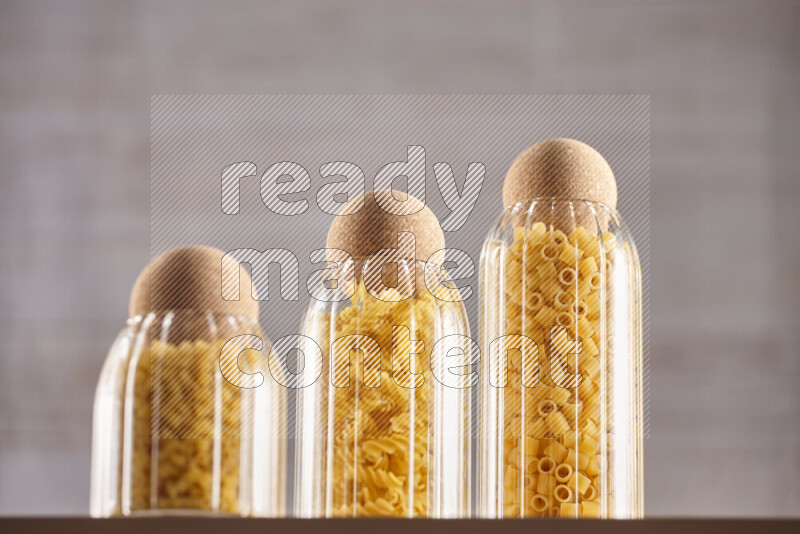 Raw pasta in glass jars on beige background