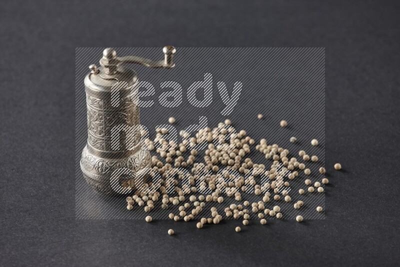 White pepper with a metal pepper grinder on black flooring