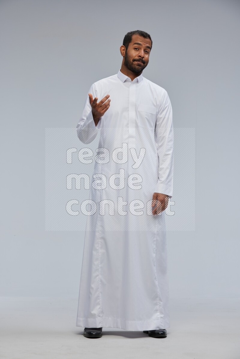 Saudi man Wearing Thob standing interacting with the camera on Gray background
