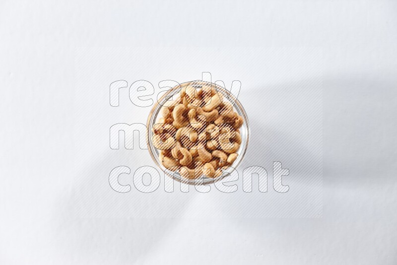 A glass bowl full of cashews on a white background in different angles
