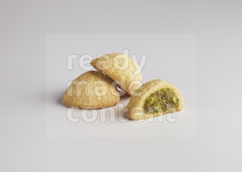 Three Pieces of Maamoul filled with pistachio paste  one of them is cut direct on white background