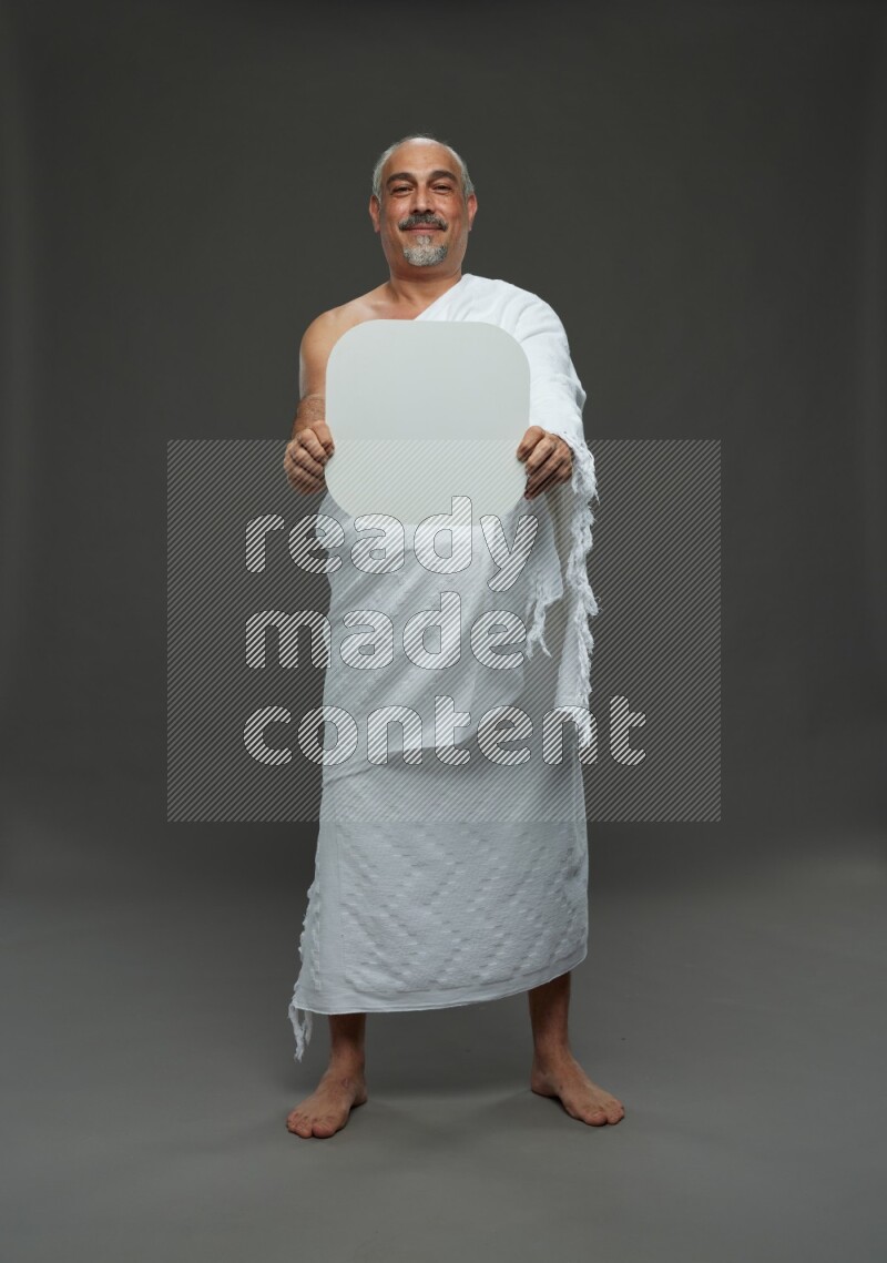 A man wearing Ehram Standing holding social media sign on gray background