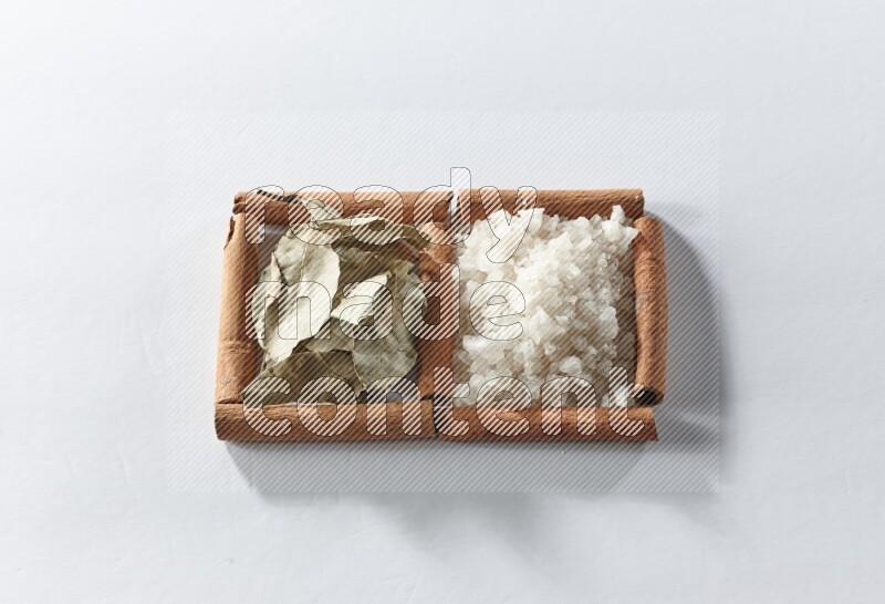 2 squares of cinnamon sticks full of white salt and laurel bay leaves on white flooring